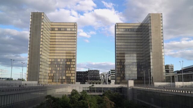 Contemporary glass facade architecture in the 13th arrondissement of Paris, France, under a cloudy blue sky.