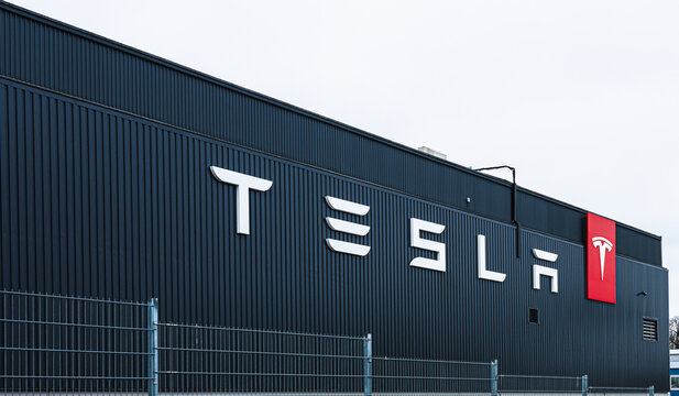 Stockholm, Sweden - March 09 2024: Tesla facility with multiple electric cars parked outside on overcast day.
