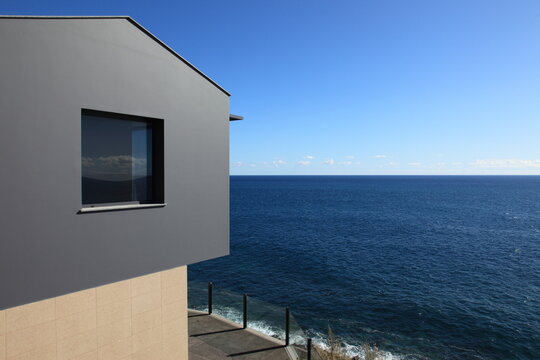 holliday house with window overlooking the ocean under a clear blue sky