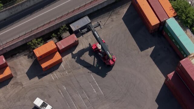Cargo Harbor Operations: An aerial view captures the dynamic activity at a cargo harbor, with a reach stacker diligently moving shipping containers.