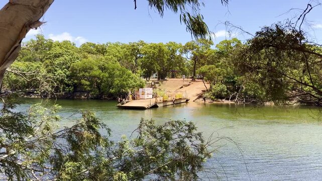 Cinematic shot of a vehicle ferry crossing the Jardine River in Cape York, northern Queensland, Australia. Remote tropical river crossing in rugged outback landscape.
