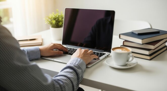 Person Working on Laptop at Bright Table with Coffee and Books