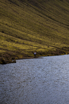 View of placid waters reflecting the overcast sky, nestled against a grassy slope in Skaftarhreppur, Iceland, Skaftarhreppur, Iceland.