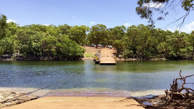 Cinematic shot of a vehicle ferry crossing the Jardine River in Cape York, northern Queensland, Australia. Remote tropical river crossing in rugged outback landscape.