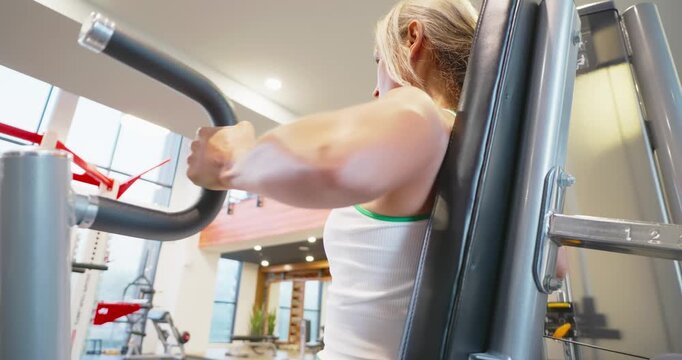 Woman Exercising on Chest Press Machine at Gym