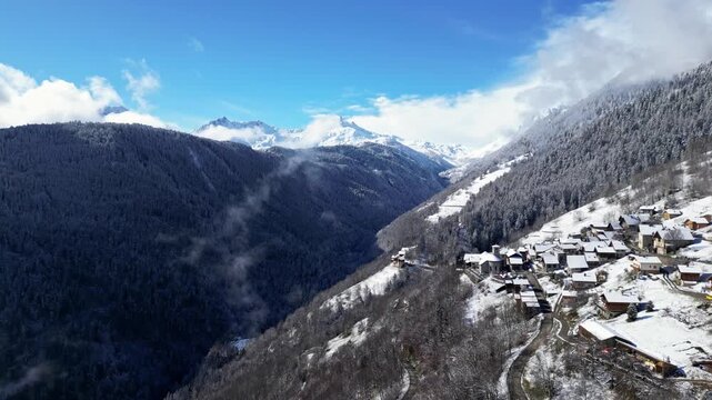 Snow covered alpine village in Tarentaise Valley with traditional houses and mountain scenery in the French Alps, Savoie, France.