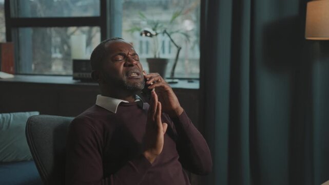 Man argues passionately, Man sits animatedly arguing and gesturing during emotionally charged phone conversation