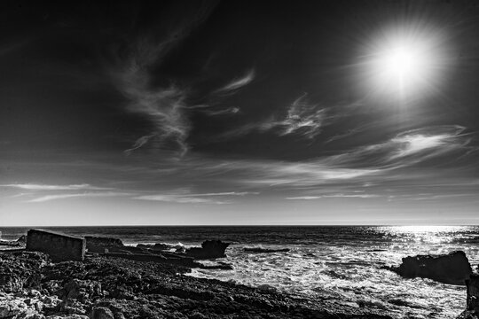 Dramatic Black and White Ocean Landscape with Sun and Clouds