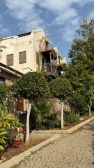 Mediterranean residential street with historic building surrounded by lush greenery under blue sky © dvoevnore