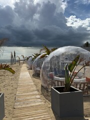 Clear beachside domes and wooden path under dramatic sky create a unique scenery background © dvoevnore