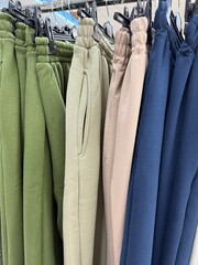 Colorful sweatpants displayed on hangers, showcasing various shades and fabric textures © dvoevnore
