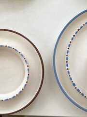 Ceramic plates with blue and brown rim on white background for dining or cooking concepts © dvoevnore