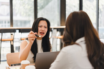 Fototapeta premium Angry business woman arguing with her colleague during a stressful meeting in a modern cafe workspace.