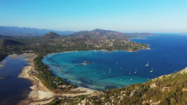 Scenic aerial view of Santa Giulia Beach with turquoise waters, anchored boats, and surrounding hills in Corsica, France.
