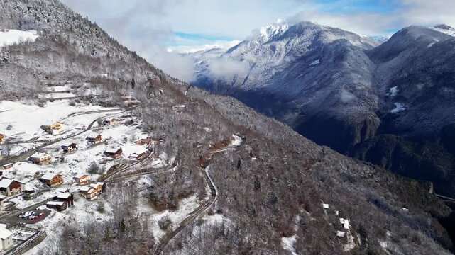 Aerial view of a snowy alpine village with chalets in Tarentaise Valley surrounded by forest and mountains in the French Alps, Savoie, France.