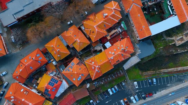 Top down aerial view of red tiled rooftops. Drone shot focusing on patterns of orange roof tiles and parking area.
