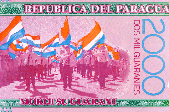 2000 Guaranies Paraguay featuring a parade of students carrying national flags. Colorful polymer currency note from South America. Money of Paraguay.