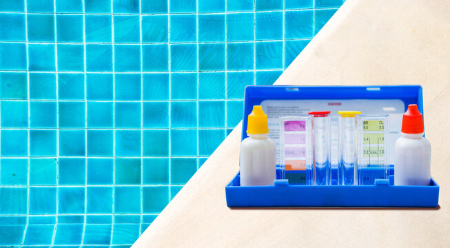 Swimming pool water tester test kit on pool deck with space on clear water background, service and maintenance industry, quality water test