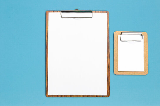 White paper on wooden clipboard on blue background, stationary and education industry, office and business concept