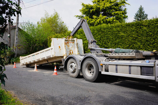THIERS, FRANCE - MARCH 16, 2026: Hooklift truck lifting a heavy industrial waste container