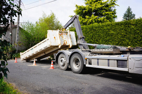 THIERS, FRANCE - MARCH 16, 2026: Hydraulic hooklift truck unloading a large steel waste container