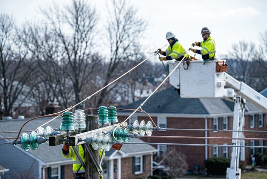 Utility workers repairing power lines from buckets