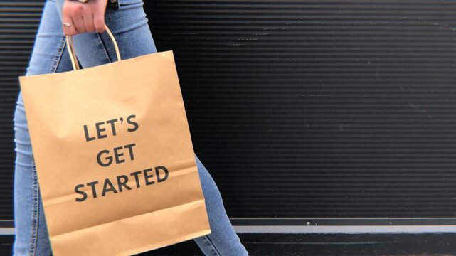 Woman carrying shopping bag with lets get started slogan text typography retail motivation and new beginnings