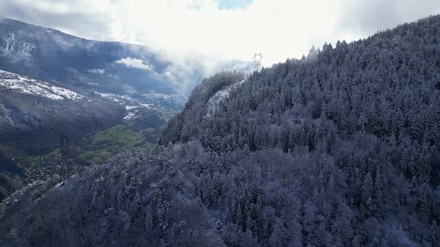 Aerial view of Tarentaise Valley with highway, alpine villages and snowy mountains covered in fog in the French Alps, Savoie, France.