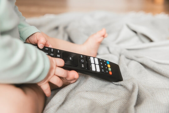 kontakt dziecka z technologią, niemowlę bawi się pilotem od telewizora