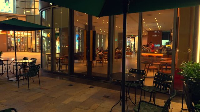 Modern urban cafe exterior at night, cozy outdoor terrace seating, city evening street, warm inviting atmosphere for business marketing, city lifestyle, and hospitality projects.