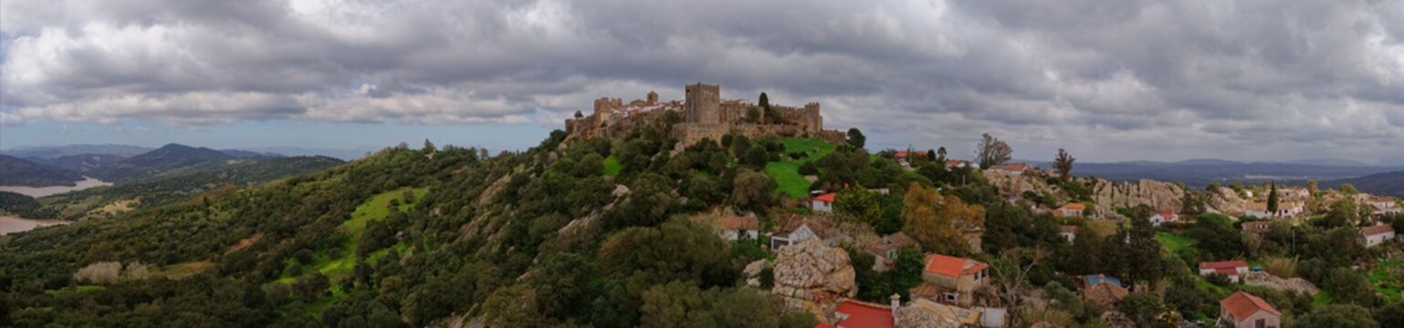 Aerial view of the Castillo de Castellar stands proudly atop a hill, its stone walls a stark contrast to the lush green landscape, Castellar de la Frontera, Andalusia, Spain.