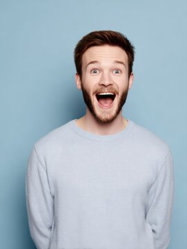 Happy surprised young man, strong emotion, studio lighting