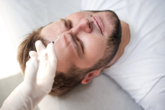 Cosmetic injection procedure on male forehead. Close-up of botox treatment for wrinkle reduction and anti-aging in modern aesthetic clinic.