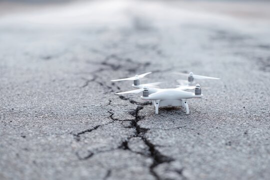 broken drone lying on cracked road symbolizing failed technology in conflict