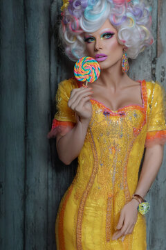Femme portrait avec perruque pastel boucl&eacute;e, robe jaune brod&eacute;e et sucette multicolore devant le visage sur fond de bois vieilli, visuel gourmand pour confiserie, mode r&eacute;tro, f&ecirc;te foraine et carnavaL