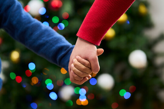 Christmas, holding hands and mother with child in home for holiday, vacation and festive season. Family, love and close up of kid for celebration, party and tradition with decoration in living room