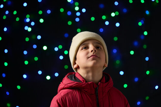 Child sitting under Christmas illumination lights in the city at night.