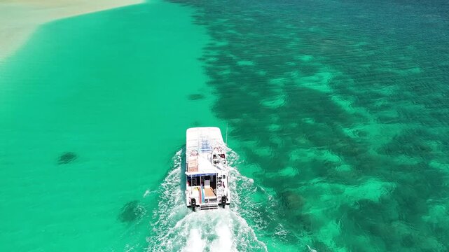 Panoramic aerial view of Coral Bay coast with a boat gliding across the tropical turquoise ocean