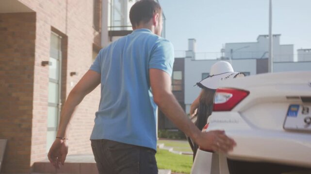 Sunlit neighborhood with joyful family arrivals, Happy family unloads car near welcoming townhome entrance