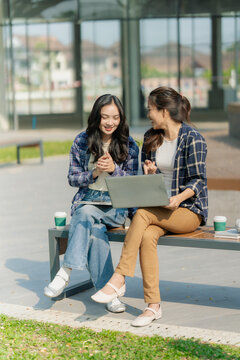 A group of young Asian female students sit on an outdoor step, reading books and chatting, studying together from their textbooks and notebooks.