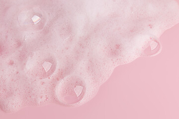 Fototapeta premium Large transparent soap bubbles, soft foam of soap, gel, detergent on a pink background. Hygiene and cleanliness concept. Top view. A copy space