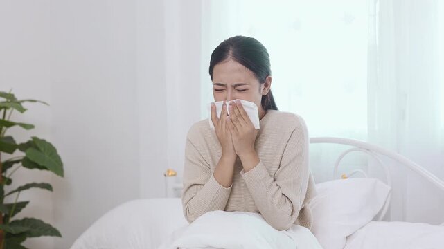 women sneezing into tissue while sitting on bed, cold and flu symptoms, allergy reaction, sick at home, healthcare concept, illness recovery, hygiene and protection.