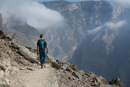 Rear view of a Man hiking along a footpath in the mountains, Jebel Shams, Oman