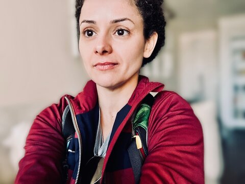 Portrait of a female hiker in sportswear with a rucksack on her back sitting on a sofa