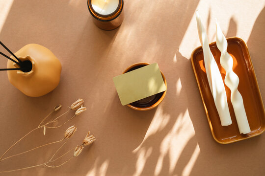 Overhead view of a blank business card on a table with a vase, dried flowers and assorted candles