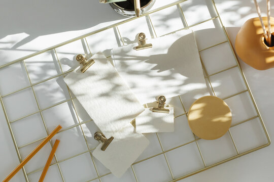 Overhead view of blank pieces of card attached to a metal grid mood board with crocodile clips on a table