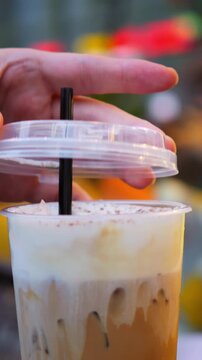 Delicate drink lid placement. Fingers gently set drink cover. Softly placing lid on beverage with care. Gentle gesture of lid placement on beverage with interaction of fingers and straw