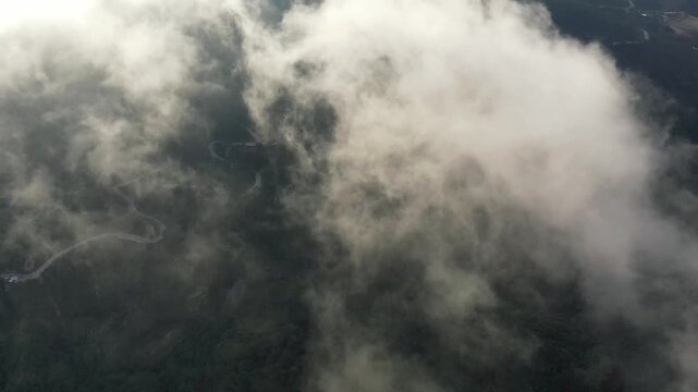 Aerial view of thick clouds floating over the lush landscape of Banaue, Philippines. Mist and fog create a dreamy, atmospheric scene from above.