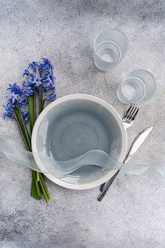 Overhead view of a spring place setting on a table with a bunch of fresh blue hyacinth flowers and a ribbon