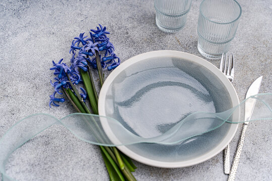 Close-up of a spring place setting on a table with a bunch of fresh blue hyacinth flowers and a ribbon